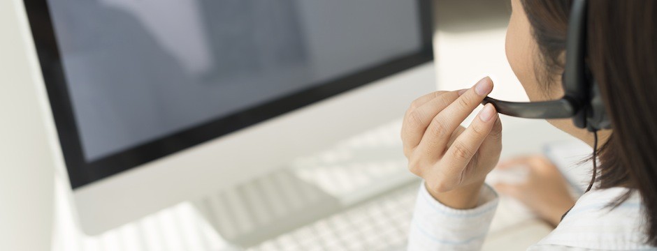 Woman with headset working on computer, view over the shoulder