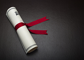 Diploma with a red ribbon on a black leather background