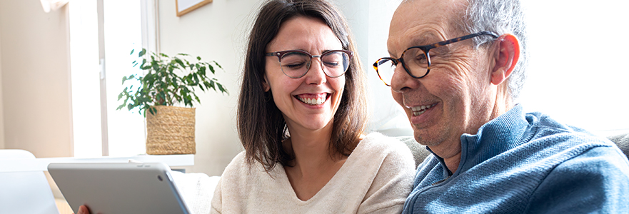 Elderly parent and child hugging while looking at a tablet